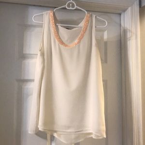 Sleeveless ivory blouse with decorated neckline